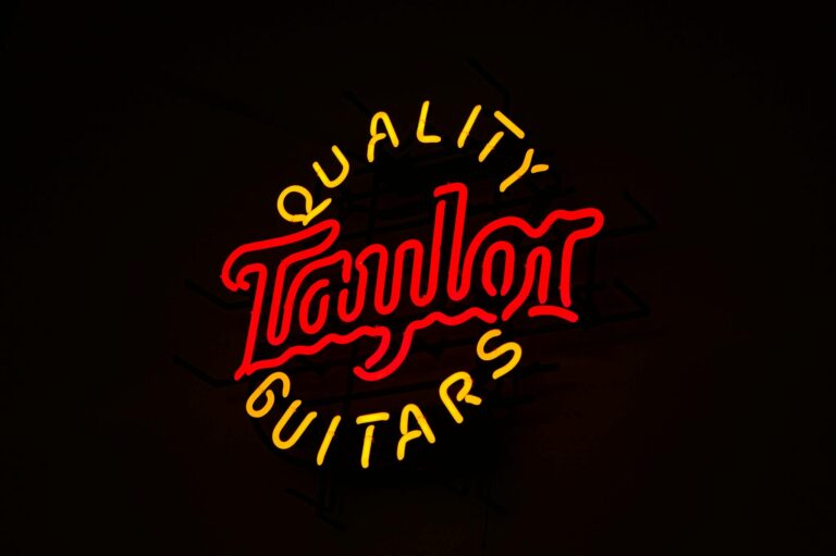 Bright neon sign featuring 'Taylor Quality Guitars', perfect for music shop or ad design use.