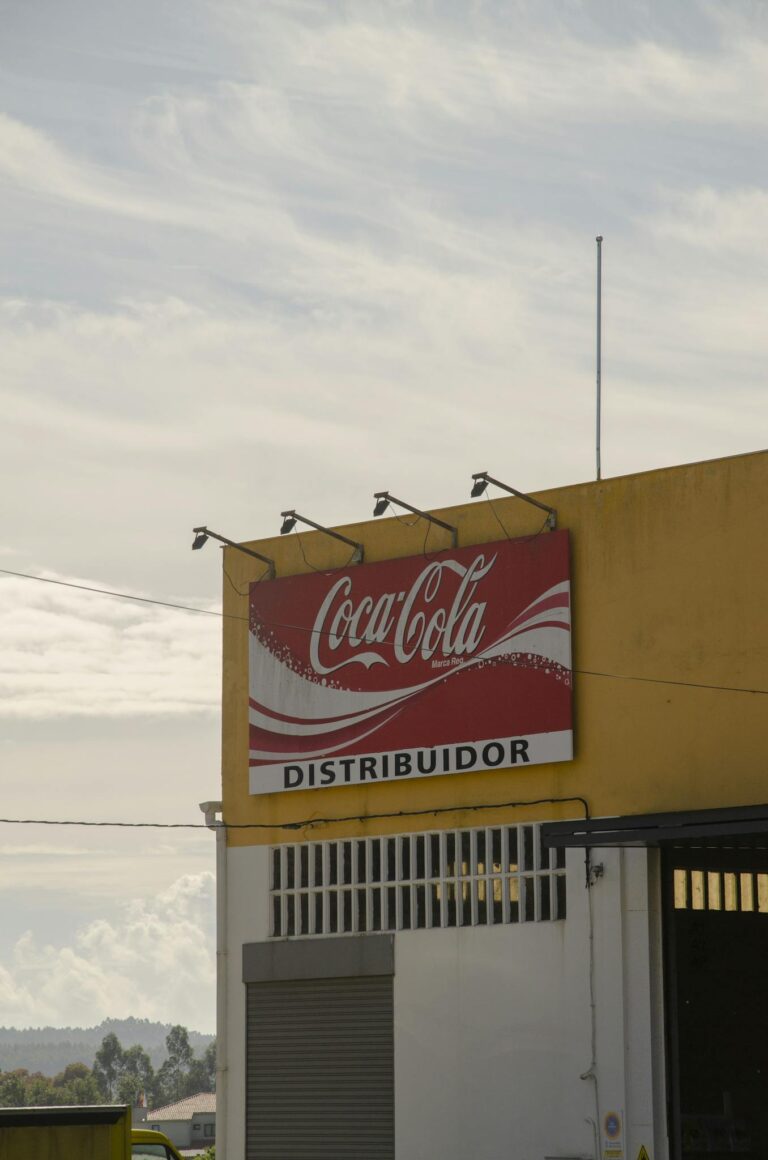 Outdoor view of Coca-Cola distributor sign on a building under a clear sky.